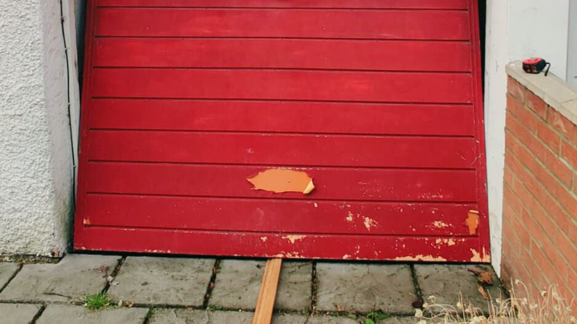 A broken manual up-and-over red garage door