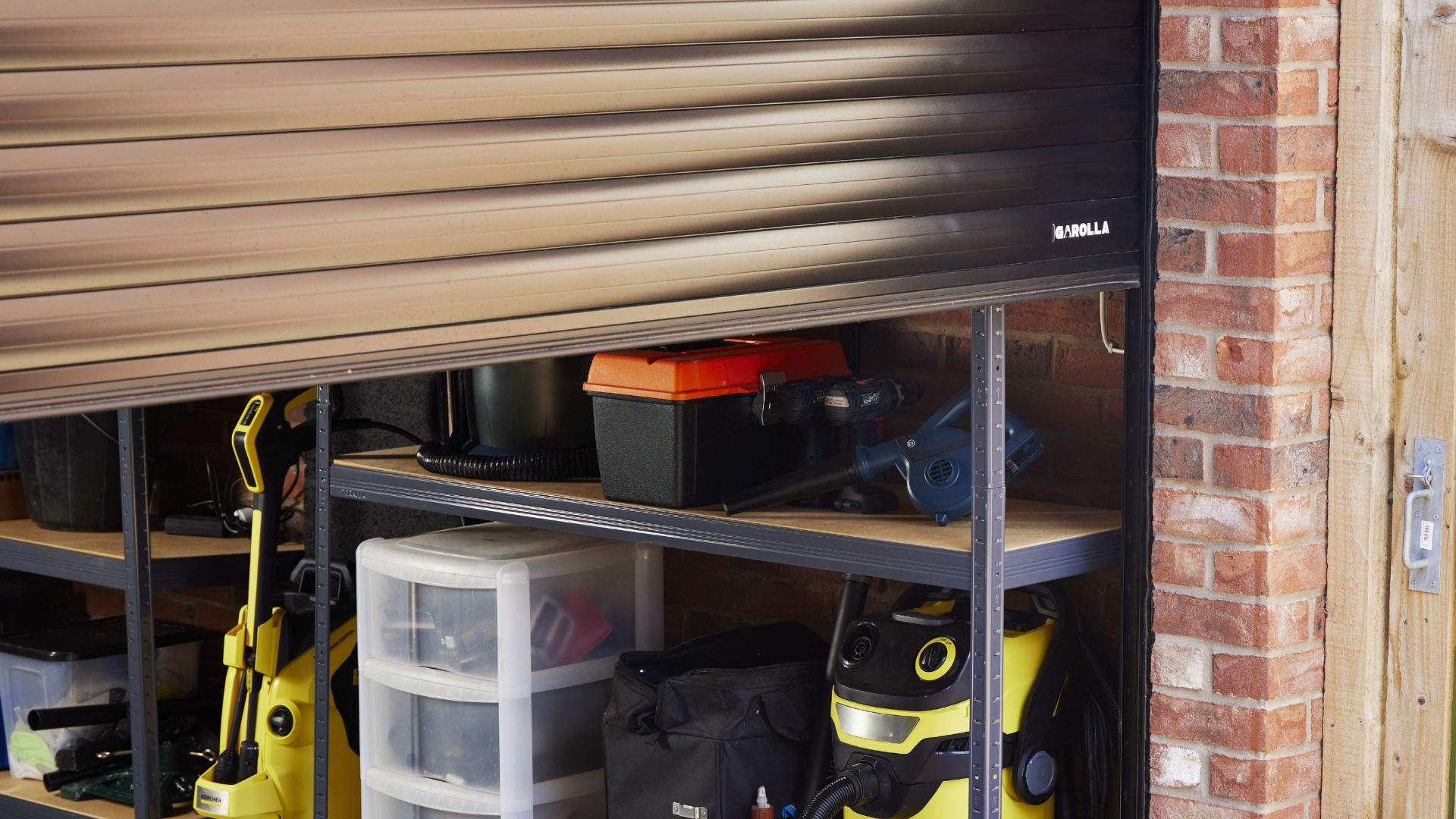 A garage featuring a garolla roller garage door and organized shelves filled with various tools and equipment.