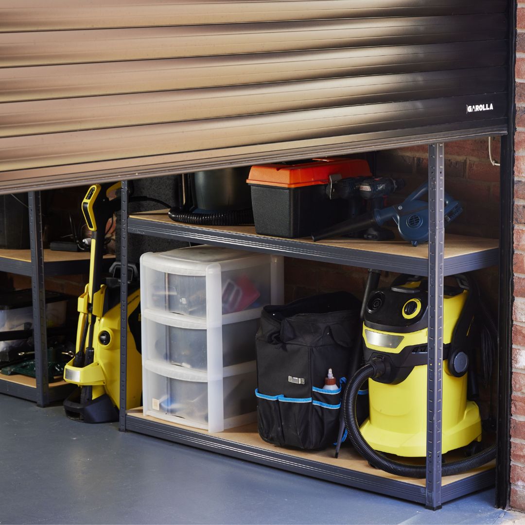 A garage featuring a garolla roller garage door and organized shelves filled with various tools and equipment.
