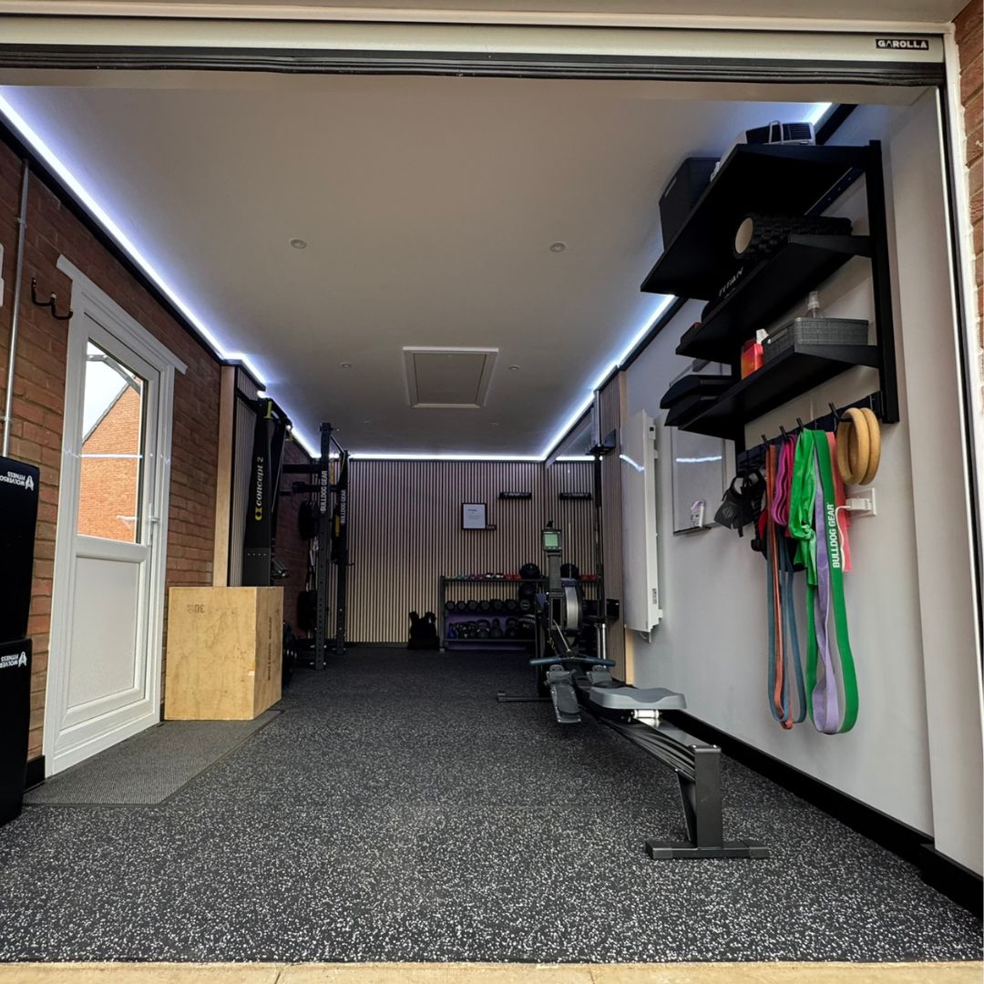 A garage scene showcasing a Garolla roller door and a barbell, highlighting a space for exercise and weight training.