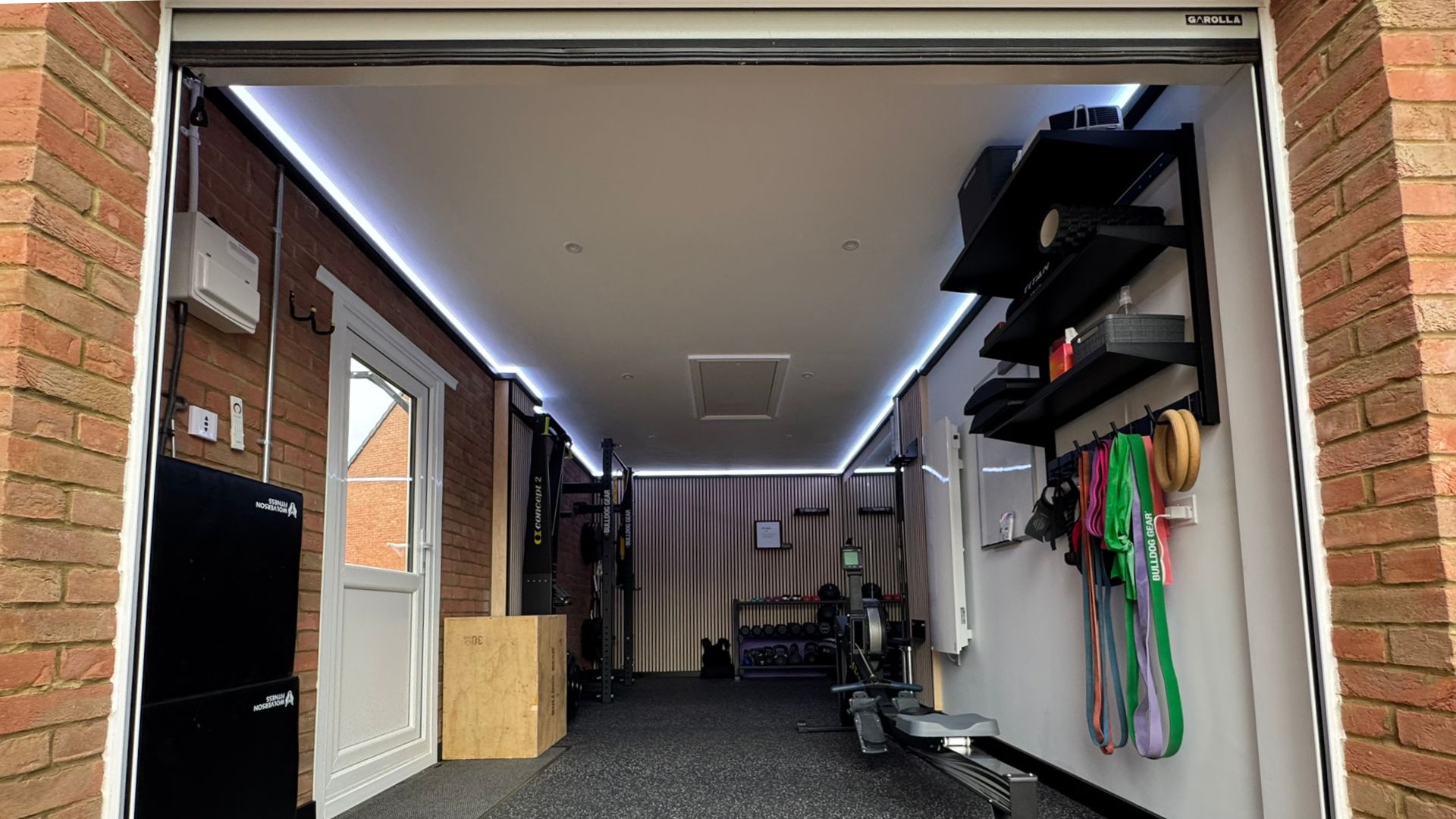 A garage scene showcasing a Garolla roller door and a barbell, highlighting a space for exercise and weight training.