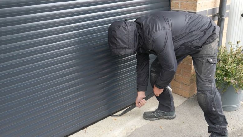 Thief attempting to break in to electric garage door with crowbar