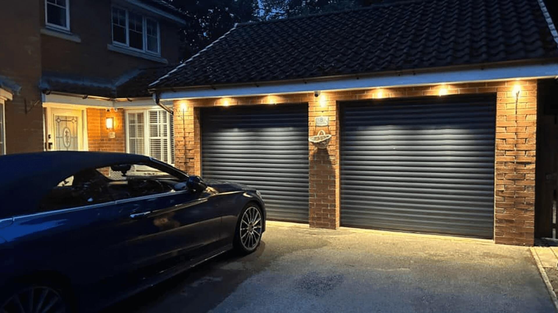 Double Garolla electric garage doors lit up on driveway