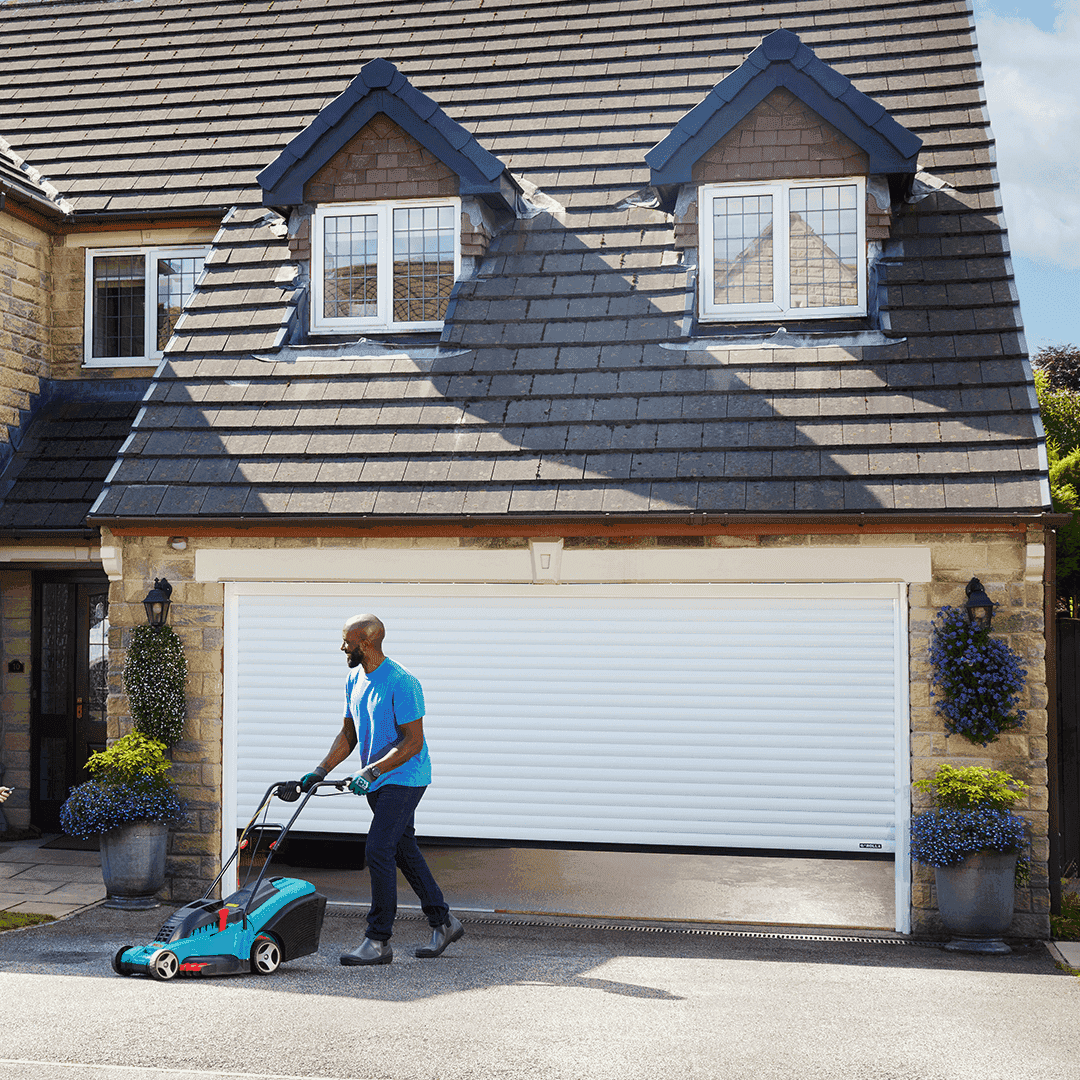 Man pushing lawnmower in front of Garolla Titan electric garage door