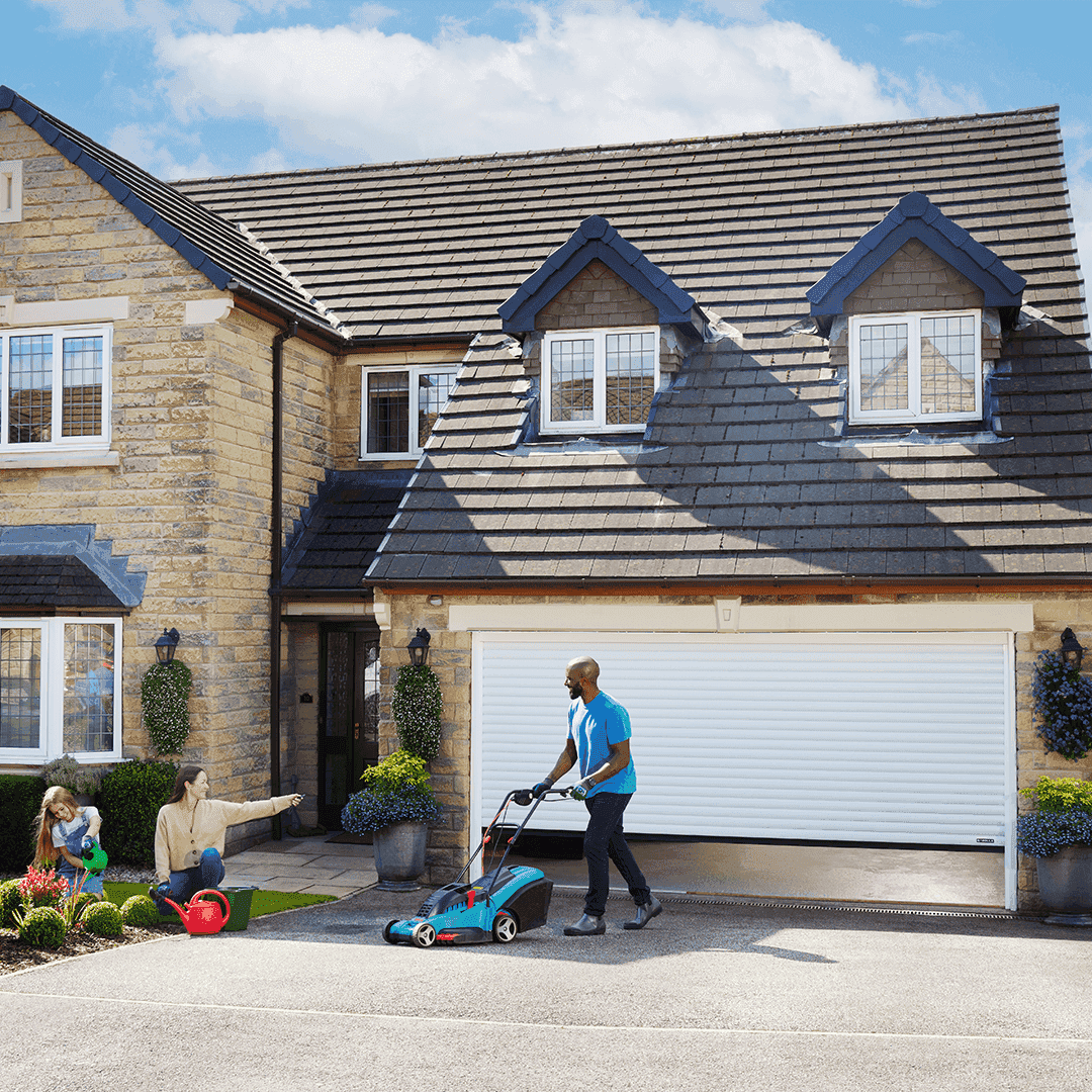 Man pushing lawnmower in front of white Garolla Titan electric garage door