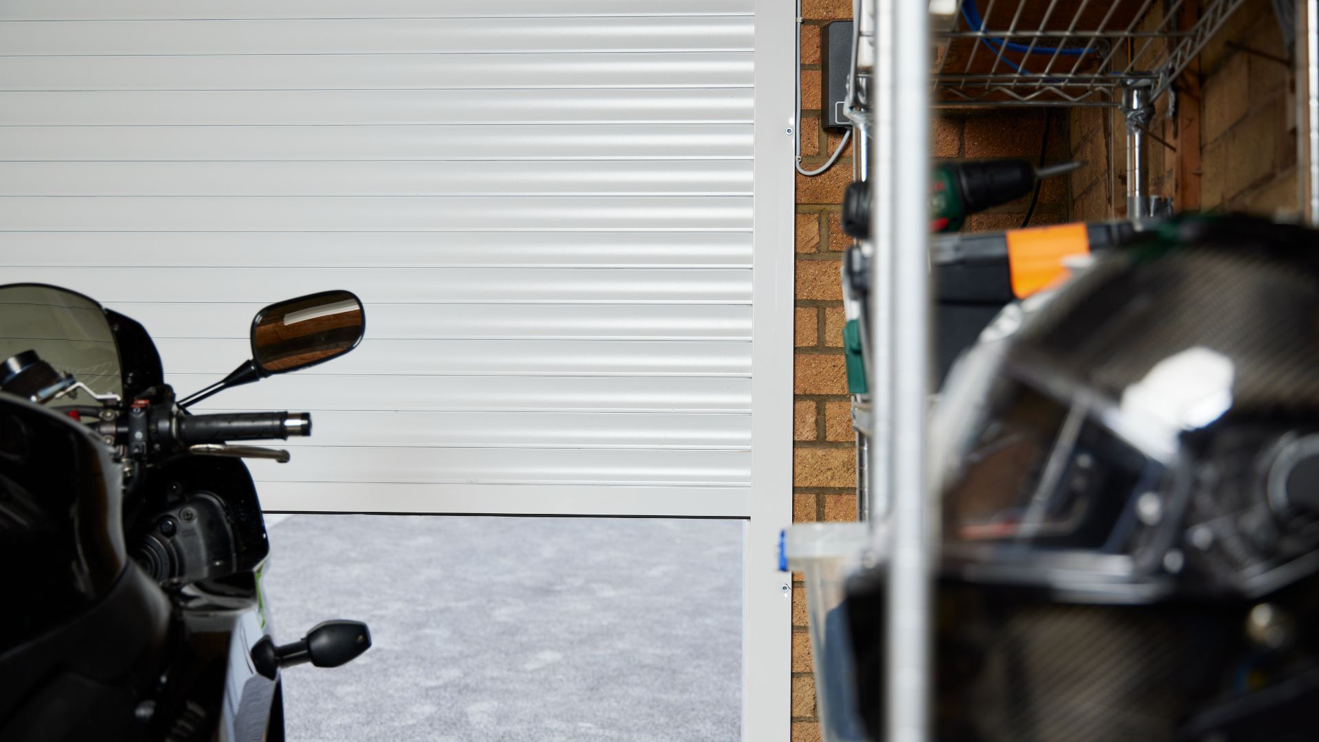 Minimalist garage interior with a modern electric roller garage door, clean flooring and organised storage space