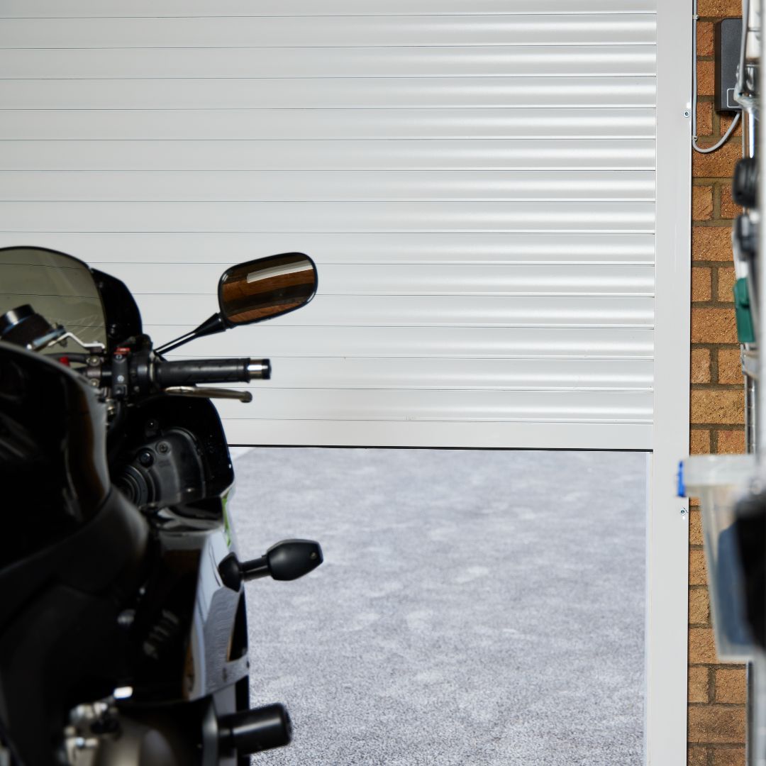 Minimalist garage interior with a modern electric roller garage door, clean flooring and organised storage space