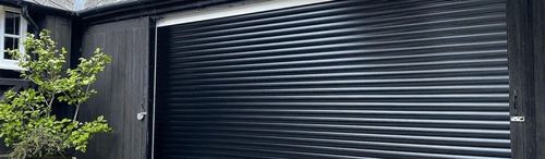 Black garage door with wooden building
