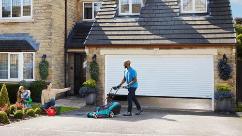Gardener pushing lawnmower from Garolla garage door